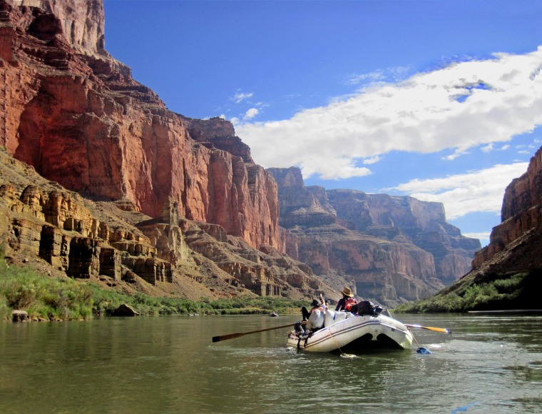 An inflatable raft floats down the Colorado River at the bottom of the Grand Canyon.