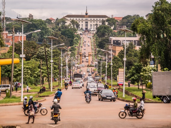 The white building that houses the Parliament of Uganda sits at the end of a busy road at the top of a hill.