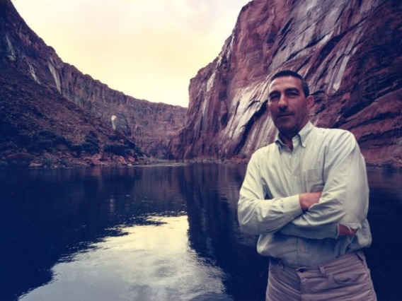 Stewart Udall poses with his arms crossed by the Colorado River