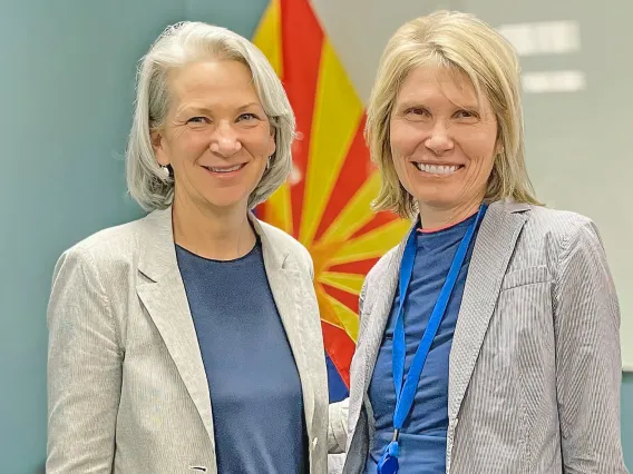 Andrea Gerlak poses with fellow Tucson Water Citizen's Water Advisory Committee member Juliet McKenna in doors in front of an Arizona flag.