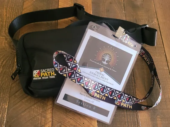 A black fanny pack with the Sacred Path logo and a lanyard from the 2024 Pascua Yaqui Tribal Enrollment Conference.