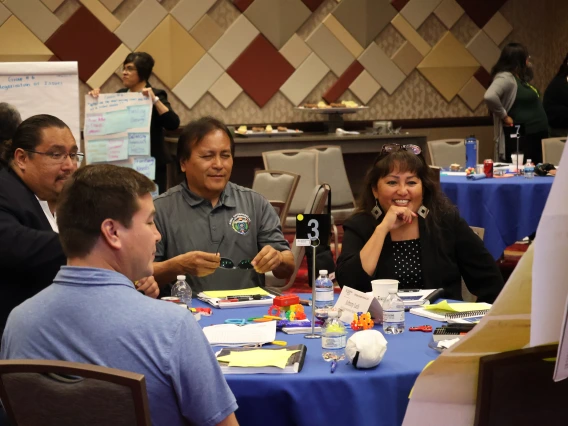 Four Native leaders chat around a round table during group work at the 2025 Emerging Leaders Seminar