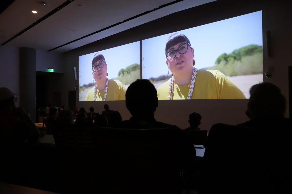 Audience members look on during the Making Arizona screening as Jacelle Ramon-Sauberan can be seen projected in two side-by-side images at the front of the room.