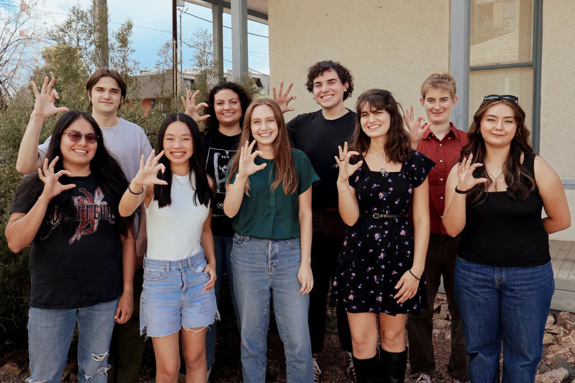 2024 Mo's Policy Scholars pose outside the Udall Center while giving the Wildcats hand signal.