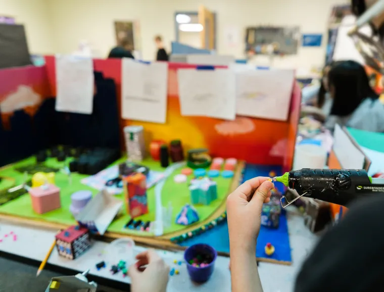 A student uses a hot glue gun to add to their Future City diorama.