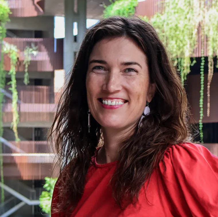 Amy Jorgensen smiles in a red blouse wat the ENR2 building.