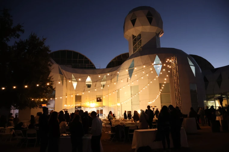 The outdoor seating area by Biosphere 2 lit up with string lights