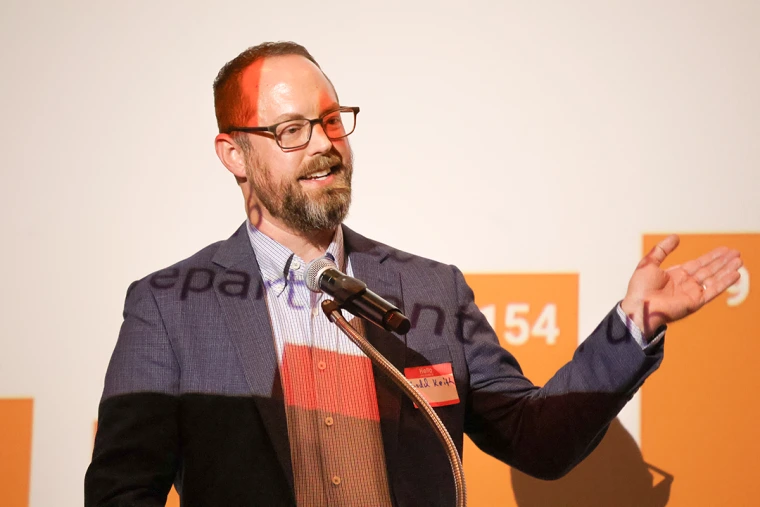 Ladd Keith presents as an orange bar chart image is projected onto and behind him