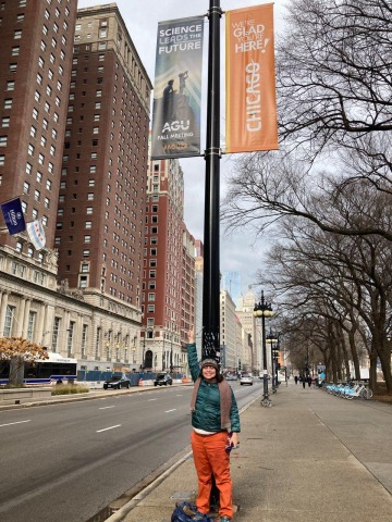 Mary Beth Jager stands under a street light displaying a banner advertising the AGU meeting in Chicago.