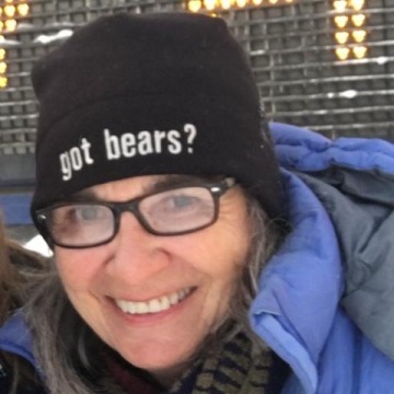 A close-up photo of Green in black-framed glasses, a blue puffy jacket and black beanie with the text "got bears?" on it.