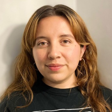 Portrait of Daniela Pinedo-Torrentera in a black t-shirt against a corner where two white walls meet.