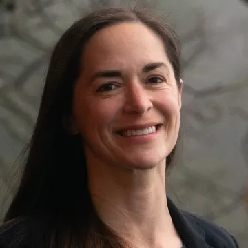 Headshot of Elizabeth Figus in a black blazer against a gray background.