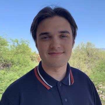 Alexander Ryan takes a selfie outside in a dark blue polo shirt.