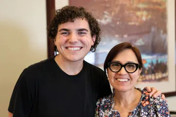 Jack Miller and Adriana Zuniga-Teran pose in the Udall Center lobby in front of a large abstract landscape painting.