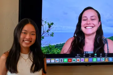 Jordyn Leith-Bailess poses with Riley Taitingfong who appears on a large television monitor via Zoom