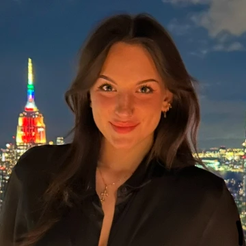 Lauren Clerihue poses in front of an illuminated city skyline at night