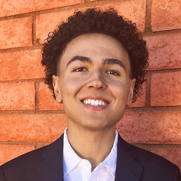 Ryan Green smiles in front of a red brick wall
