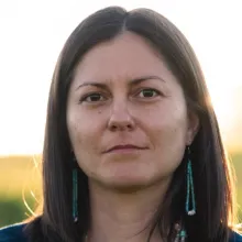 Portrait of Renee Hutchins in beaded turquoise earrings backlit by a setting sun