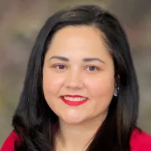 Portrait of Danielle McLean in a red blouse with a blurred brown and green background