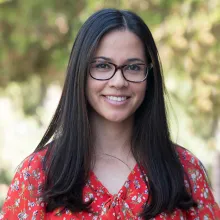 Jennifer Mason poses outdoors in a red blouse and glasses.