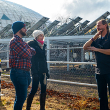 Greg Barron-Gafford, Andrea Gerlak and another researcher discuss agrivoltaics in front of a solar array at Biosphere 2.