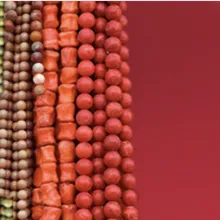 Strings of multi-colored beads cover the left side of the image over a dark-red background.