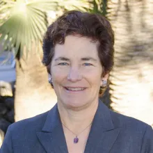 Kathy Jacobs outdoors in a blue blazer with palm trees in the background.