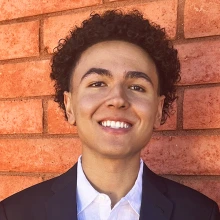 Ryan Green smiles in front of a red brick wall