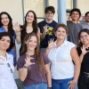 Nine of the 10 2025-26 Mo's Policy Scholars flash wildcat hand signs on the steps of the Udall Center