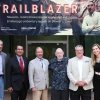Bradley Udall, Jonathan Nez, Tom Udall, Burr Udall, Steve Hussman, and Tess Udall pose under the 'Trailblazer' exhibit banner at U of A Library Special Collections