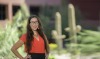 Stephanie Russo Carroll poses in front of saguaro cactus in a red shirt.